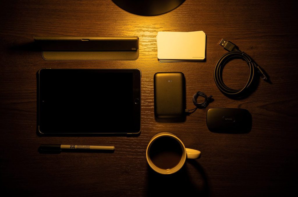 The night-before table: tablet, stand, power bank, printed windshield cards, and a hotspot laid out under a lamp
